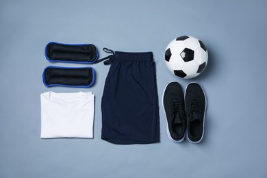 Photo of Sportswear, sneakers and soccer ball on grey background, flat lay