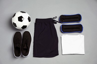 Photo of Sportswear, sneakers and soccer ball on grey background, flat lay