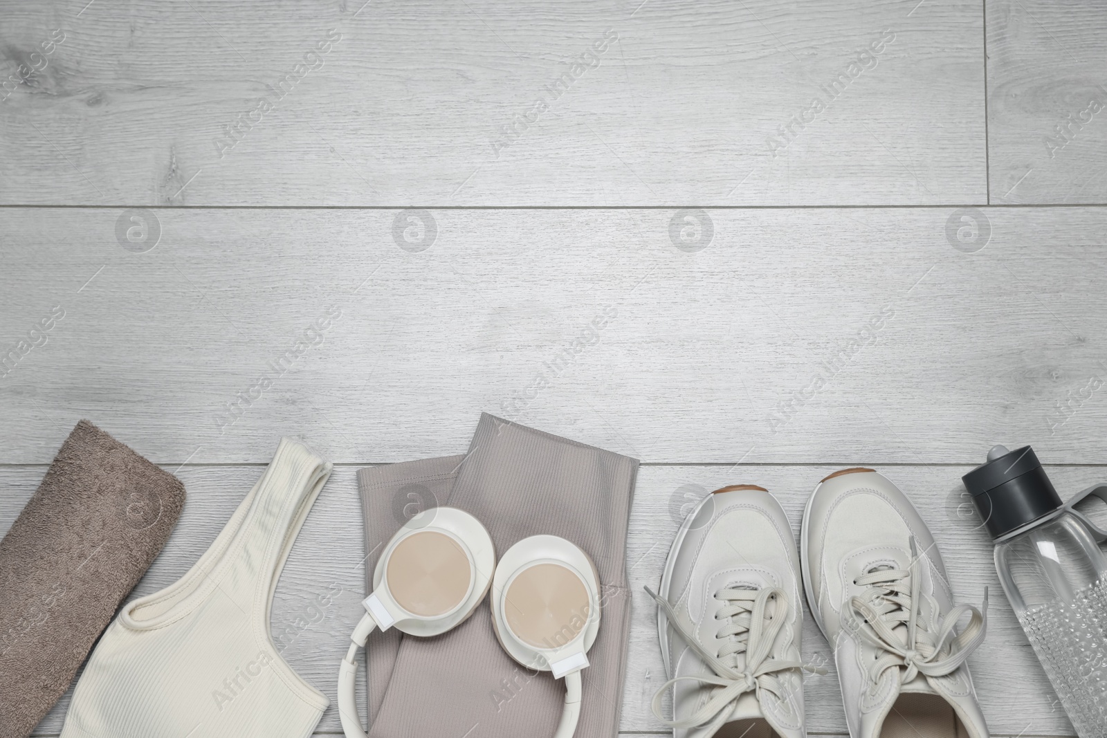Sportswear, sneakers, water bottle and towel on floor, flat lay. Space for text Photo of Sportswear, sneakers, water bottle and towel on floor, flat lay. Space for text