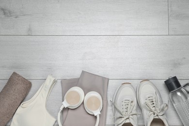 Photo of Sportswear, sneakers, water bottle and towel on floor, flat lay. Space for text