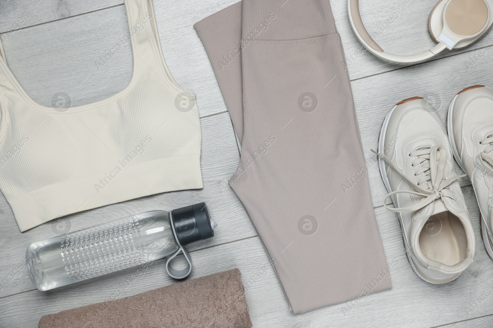 Sportswear, sneakers, water bottle and towel on floor, flat lay Photo of Sportswear, sneakers, water bottle and towel on floor, flat lay