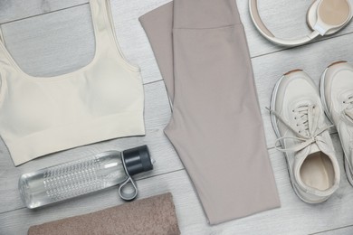 Photo of Sportswear, sneakers, water bottle and towel on floor, flat lay