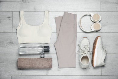 Photo of Sportswear, sneakers, water bottle and towel on floor, flat lay