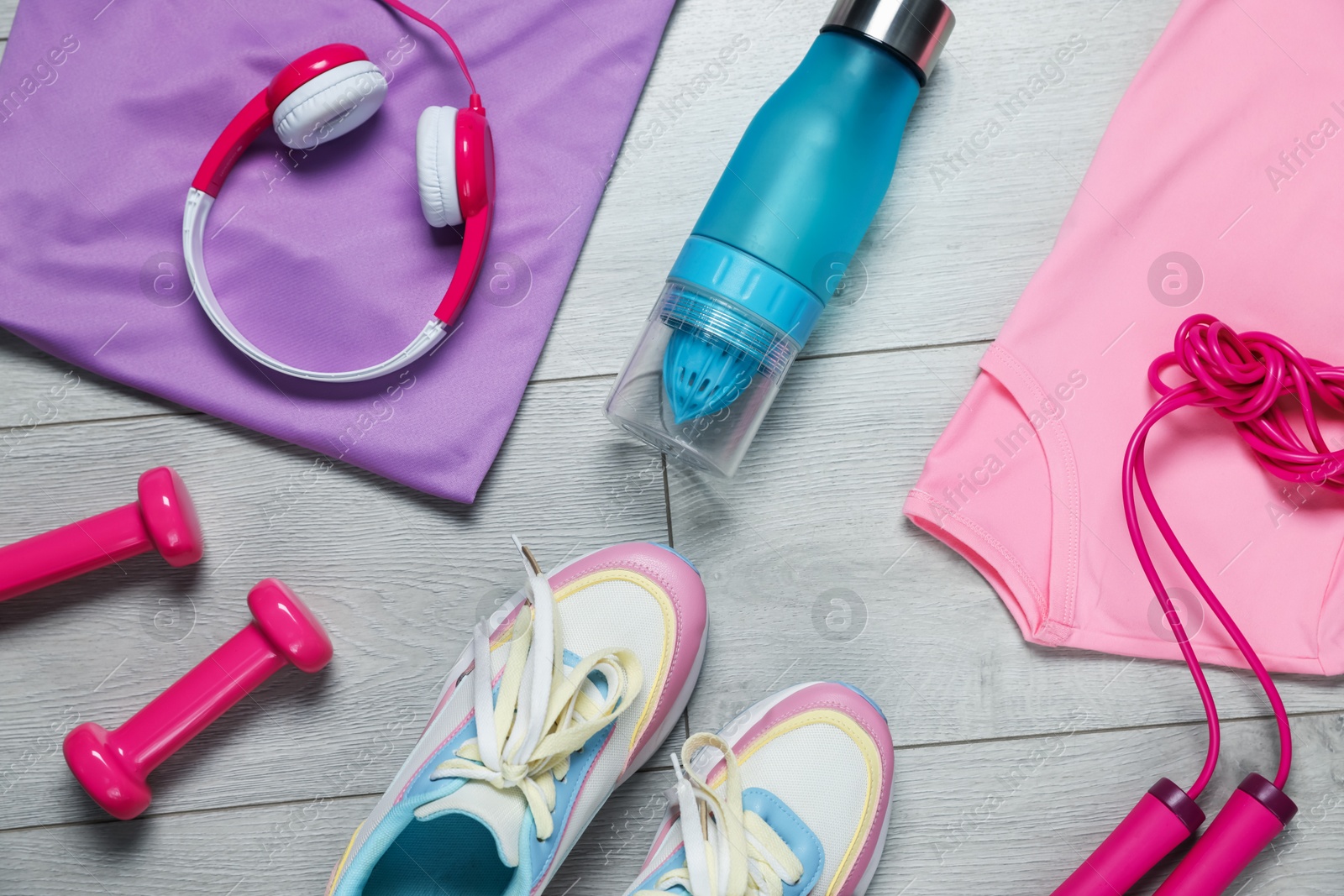 Sportswear, sneakers, skipping rope, water bottle, headphones and dumbbells on floor, flat lay Photo of Sportswear, sneakers, skipping rope, water bottle, headphones and dumbbells on floor, flat lay