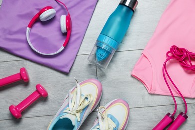 Photo of Sportswear, sneakers, skipping rope, water bottle, headphones and dumbbells on floor, flat lay