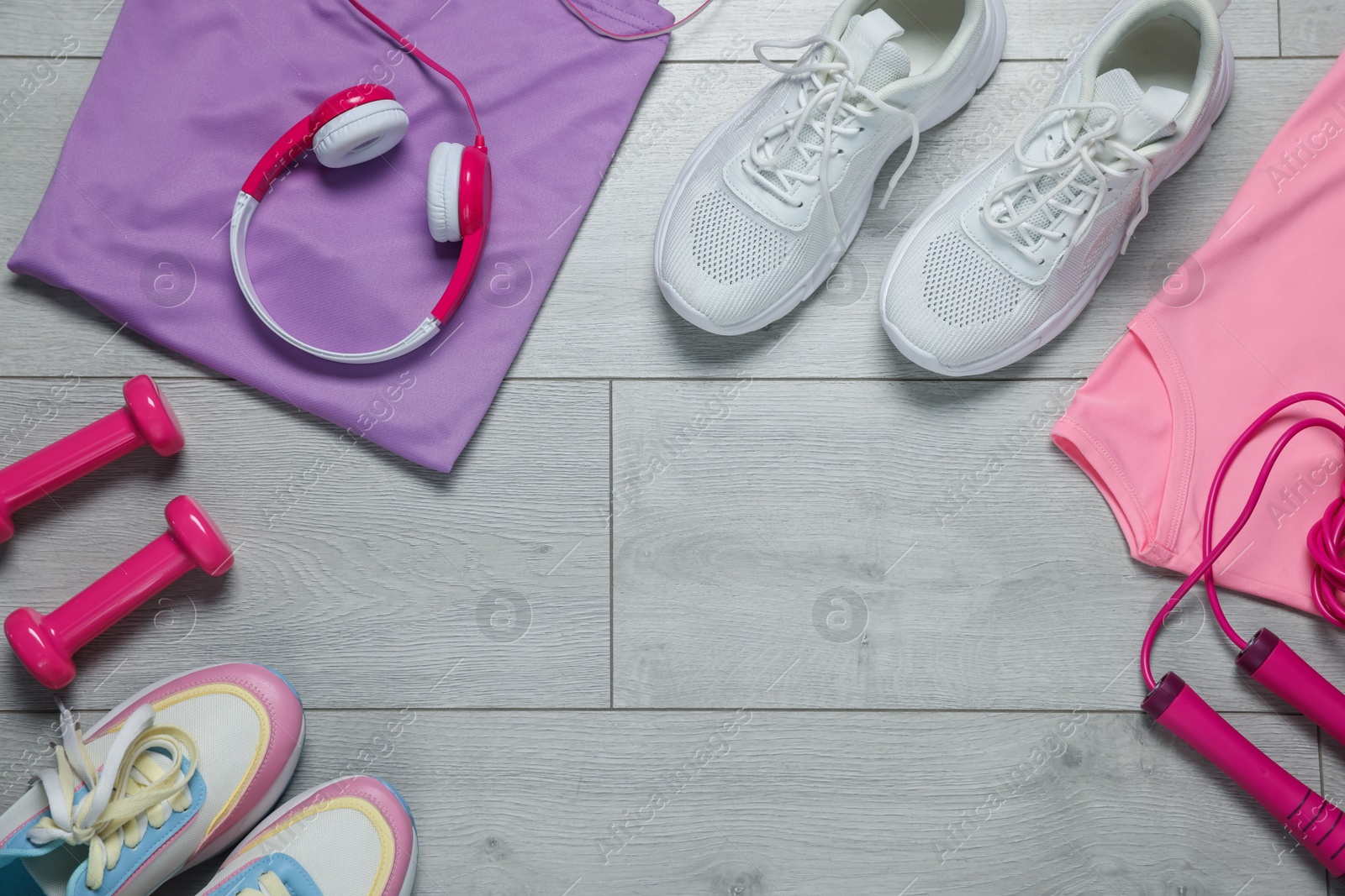 Sportswear, sneakers, skipping rope, headphones and dumbbells on floor, flat lay. Space for text Photo of Sportswear, sneakers, skipping rope, headphones and dumbbells on floor, flat lay. Space for text