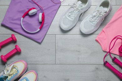 Photo of Sportswear, sneakers, skipping rope, headphones and dumbbells on floor, flat lay. Space for text