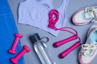 Photo of Sportswear, sneakers, skipping rope, dumbbells and water bottle on grey background, flat lay