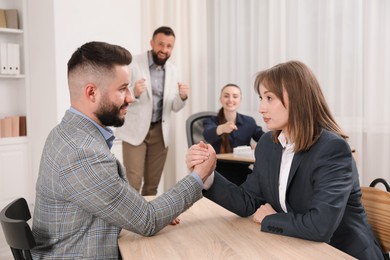 Photo of Businesspeople arm wrestling at wooden table in office, selective focus