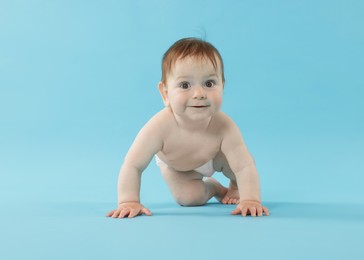 Photo of Cute little baby crawling on light blue background