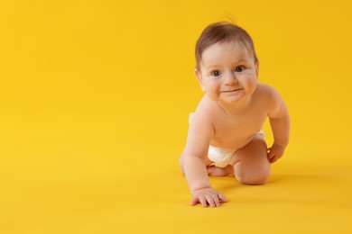 Photo of Cute little baby crawling on yellow background. Space for text