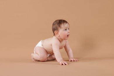 Photo of Cute little baby crawling on beige background