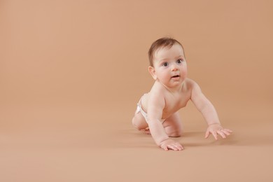 Photo of Cute little baby crawling on beige background. Space for text