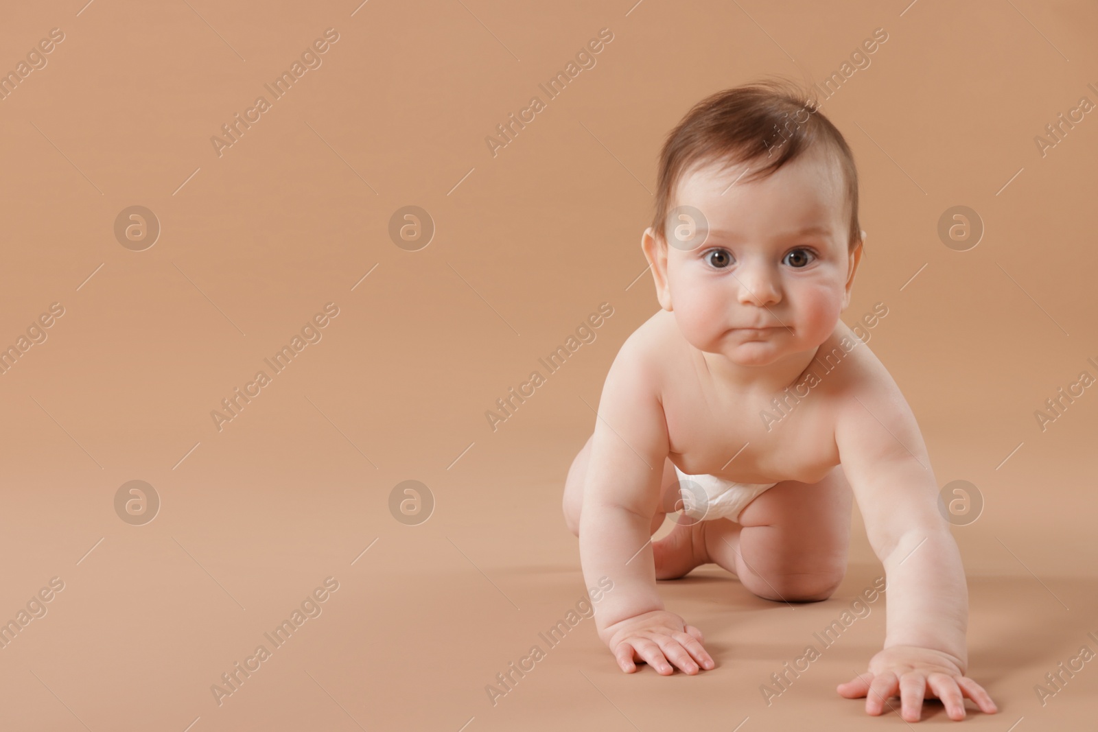 Cute little baby crawling on beige background. Space for text Photo of Cute little baby crawling on beige background. Space for text