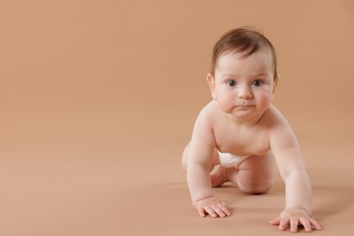 Photo of Cute little baby crawling on beige background. Space for text