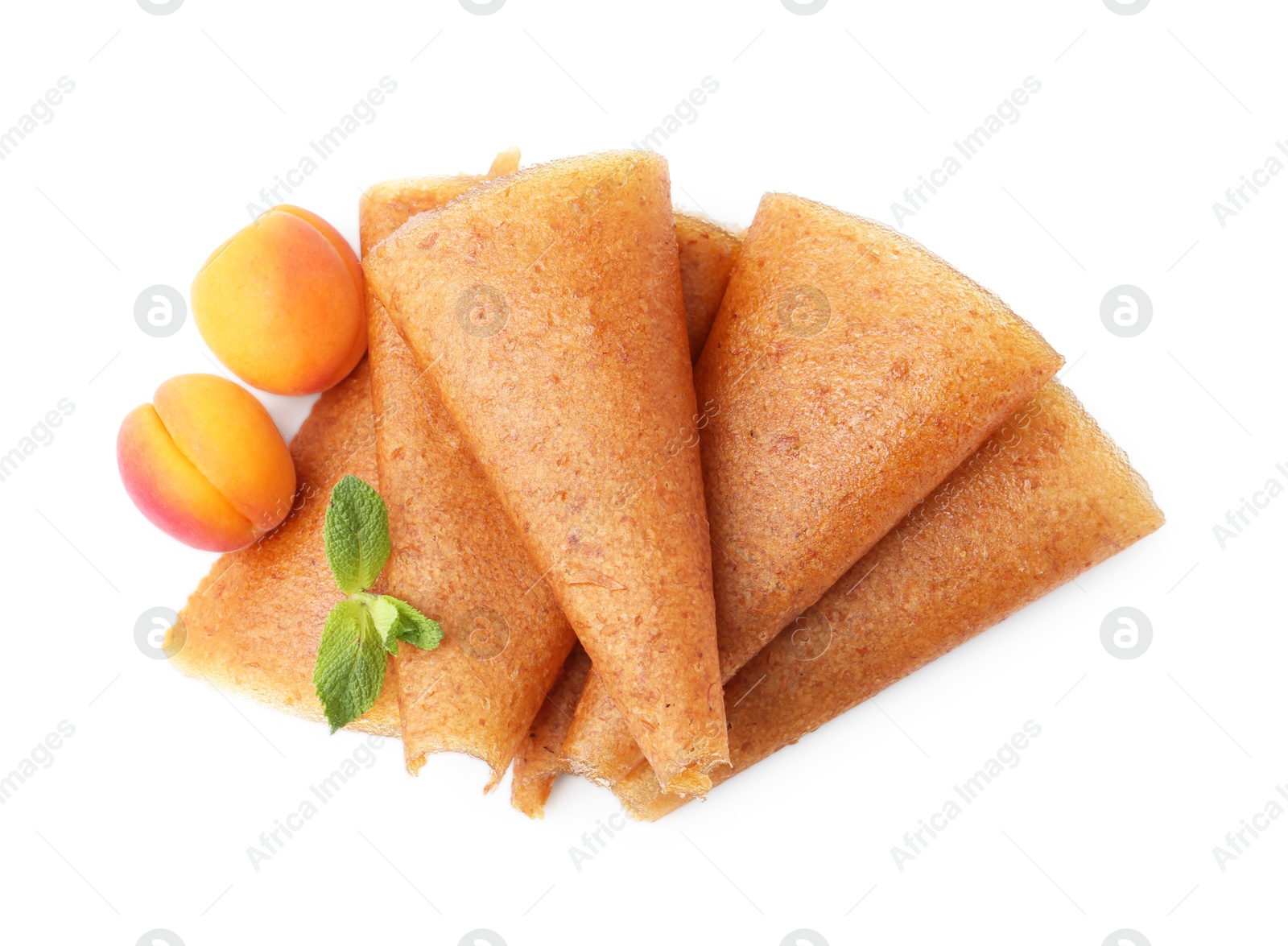 Delicious fruit leather rolls and apricots isolated on white, top view Photo of Delicious fruit leather rolls and apricots isolated on white, top view