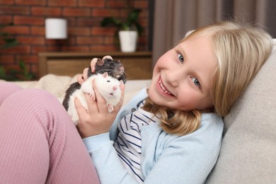 Photo of Little girl with cute rats on sofa at home