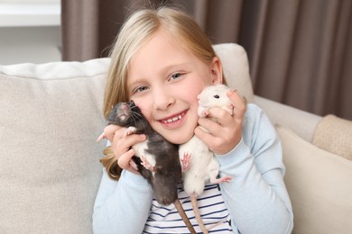 Photo of Little girl with cute rats on sofa at home