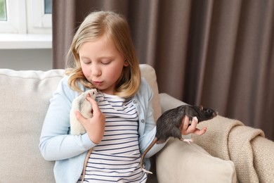Photo of Little girl with cute rats on sofa at home