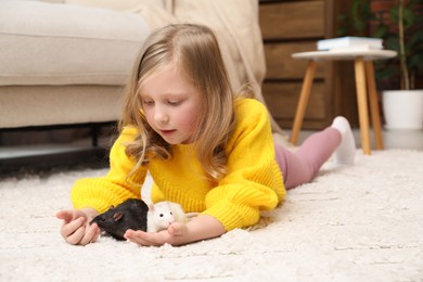 Photo of Little girl with cute rats on floor at home