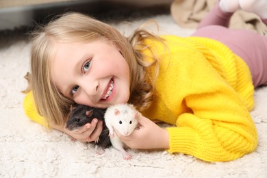 Photo of Little girl with cute rats on floor at home