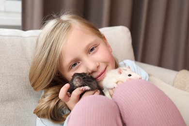 Photo of Little girl with cute rats on sofa at home
