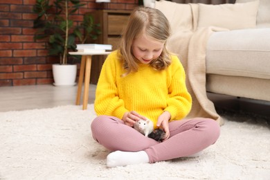 Photo of Little girl with cute rats on floor at home