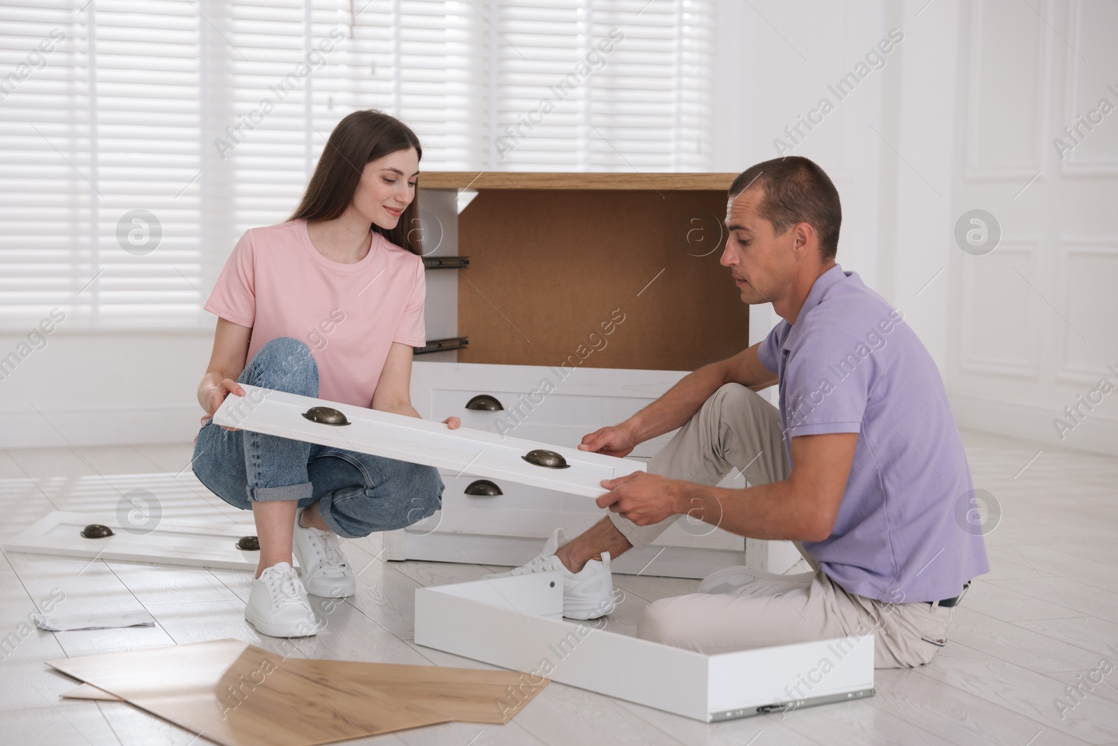 Couple assembling furniture on floor at home Photo of Couple assembling furniture on floor at home