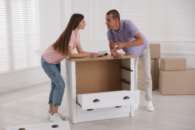 Photo of Happy couple with manual assembling furniture on floor at home