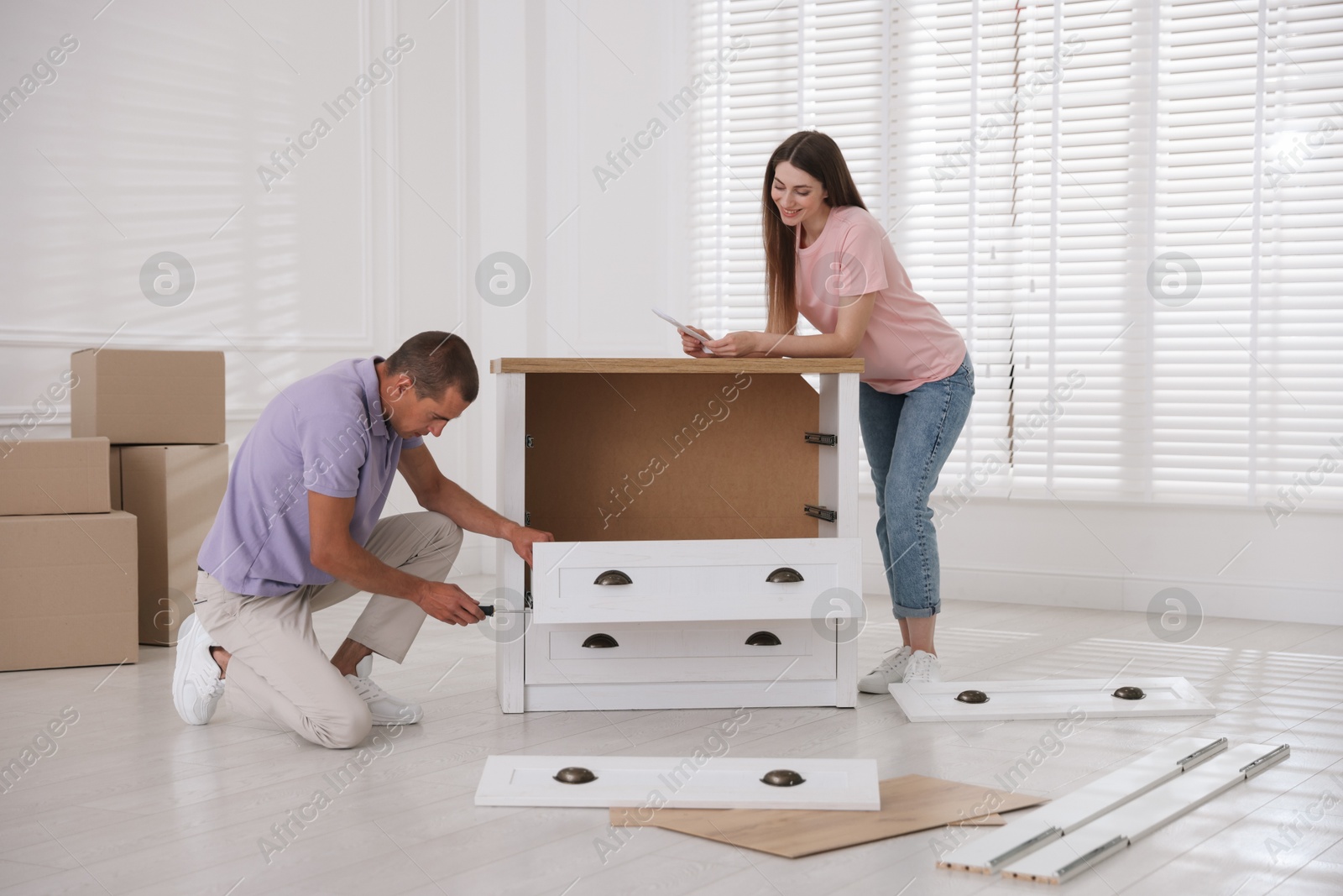 Photo of Happy couple with manual assembling furniture on floor at home