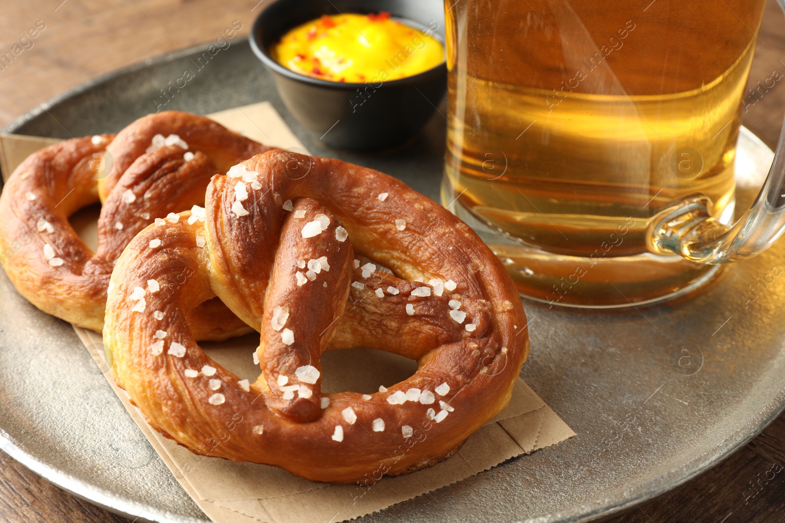 Tasty pretzels, sauce and glass of beer on wooden table, closeup Photo of Tasty pretzels, sauce and glass of beer on wooden table, closeup