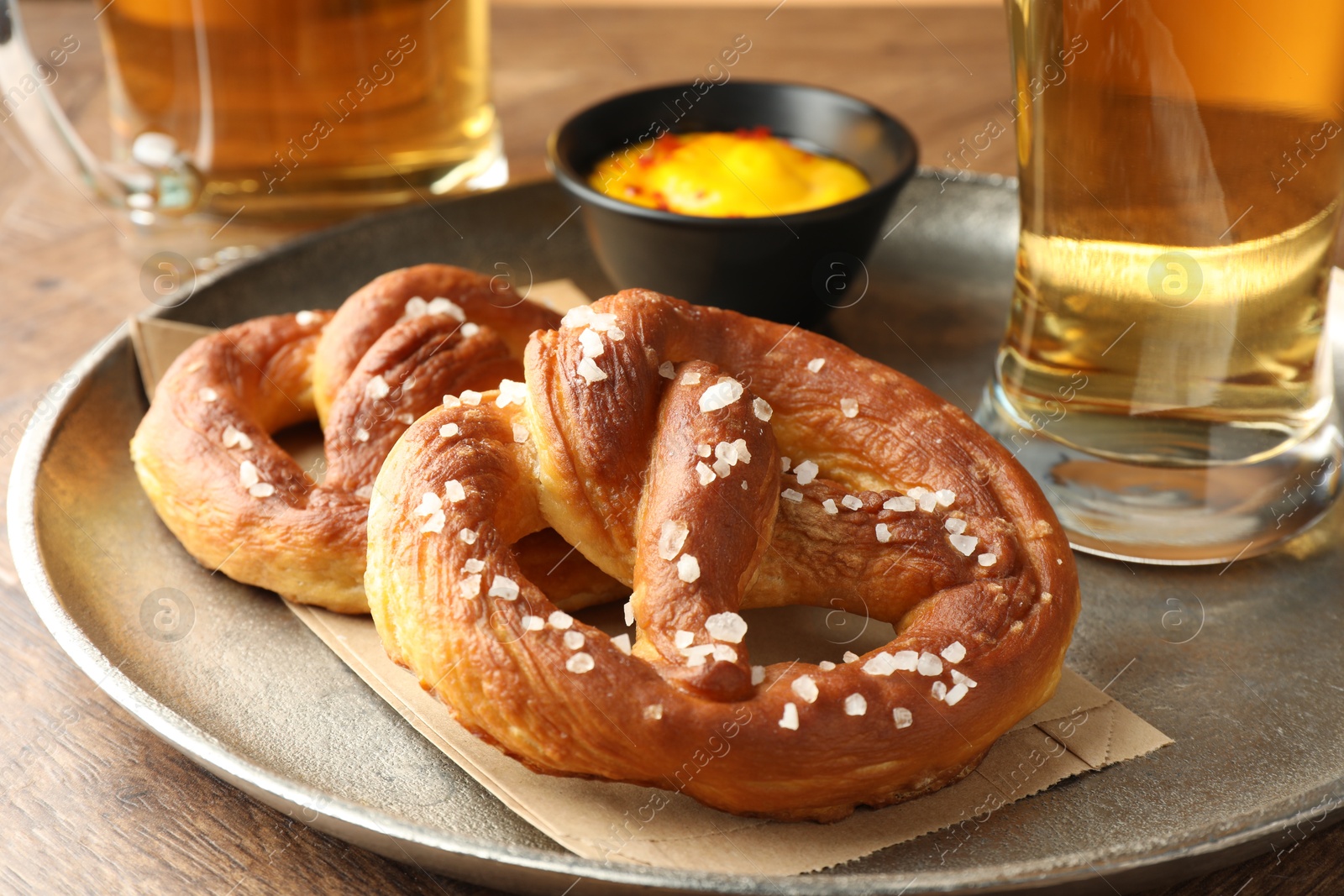 Tasty pretzels, sauce and glasses of beer on wooden table, closeup Photo of Tasty pretzels, sauce and glasses of beer on wooden table, closeup