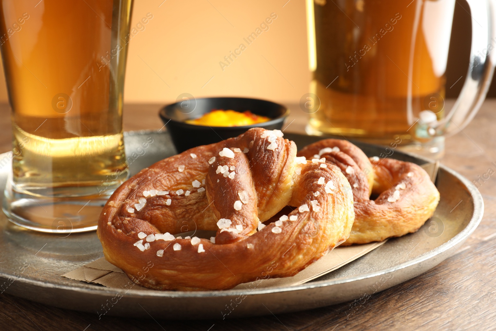 Tasty pretzels, sauce and glasses of beer on wooden table against beige gradient background, closeup Photo of Tasty pretzels, sauce and glasses of beer on wooden table against beige gradient background, closeup