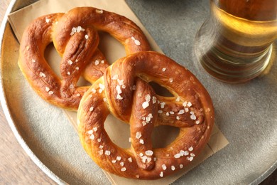 Photo of Tasty pretzels and beer on wooden table, top view