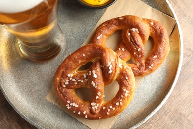 Photo of Tasty pretzels and beer on wooden table, top view
