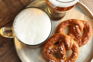 Photo of Tasty pretzels and beer on wooden table, top view