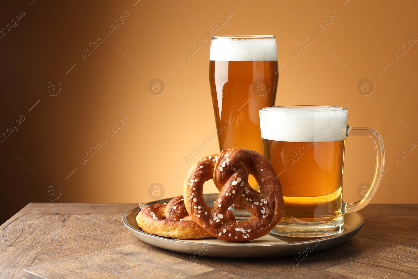 Tasty pretzels and beer on wooden table against golden gradient background, closeup Photo of Tasty pretzels and beer on wooden table against golden gradient background, closeup