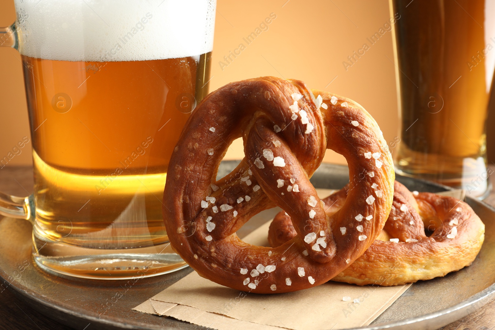 Tasty pretzels and beer on table against golden gradient background, closeup Photo of Tasty pretzels and beer on table against golden gradient background, closeup