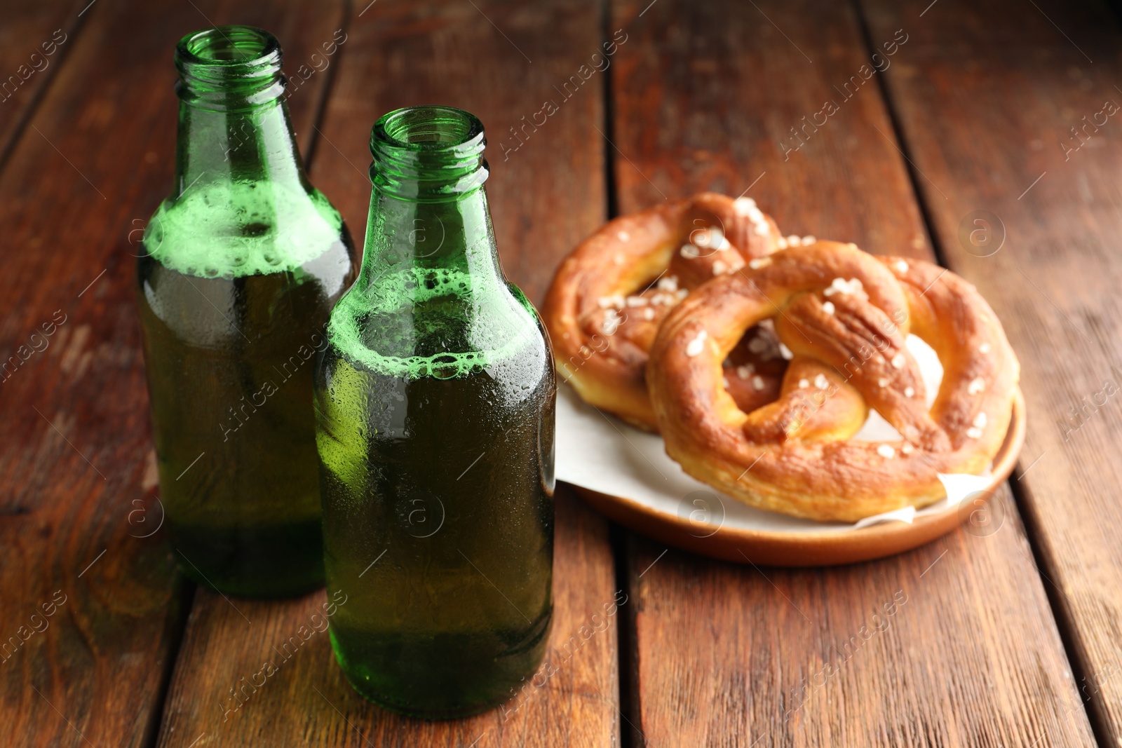 Bottles of beer and tasty pretzels on wooden table, selective focus Photo of Bottles of beer and tasty pretzels on wooden table, selective focus