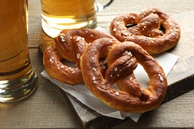 Photo of Tasty pretzels and beer on wooden table, closeup