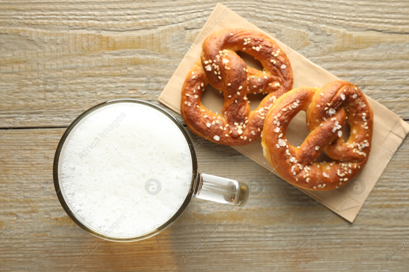 Tasty pretzels and glass mug of beer on wooden table, flat lay Photo of Tasty pretzels and glass mug of beer on wooden table, flat lay