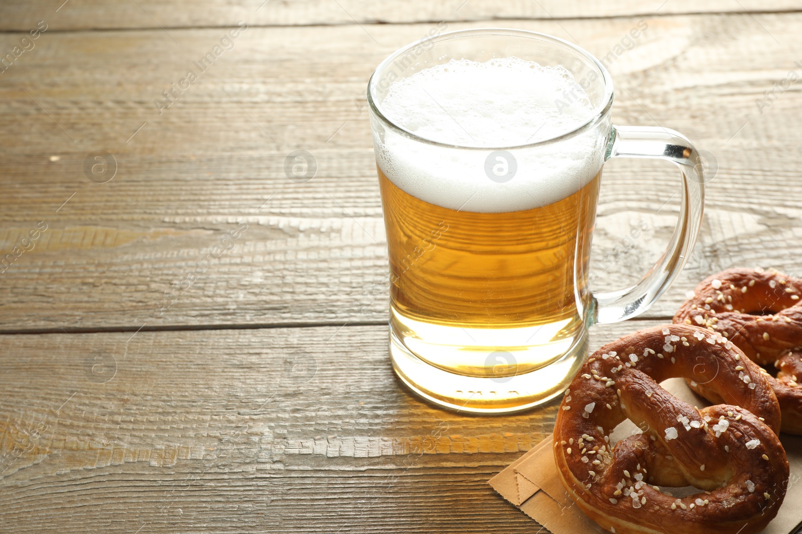 Tasty pretzels and glass mug of beer on wooden table, closeup. Space for text Photo of Tasty pretzels and glass mug of beer on wooden table, closeup. Space for text