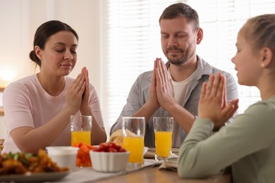 Photo of Family praying together before dinner at table indoors