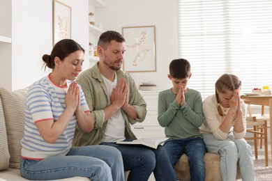 Photo of Family with Bible praying together at home
