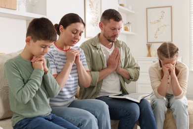 Photo of Family with Bible praying together at home