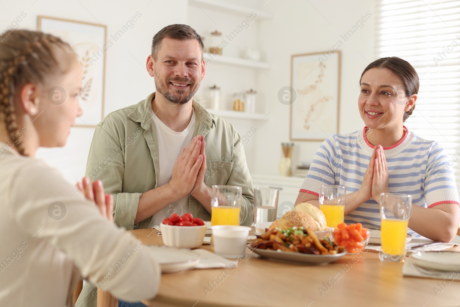 Family praying together before dinner at table indoors Photo of Family praying together before dinner at table indoors