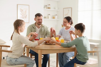 Photo of Family praying together before dinner at table indoors