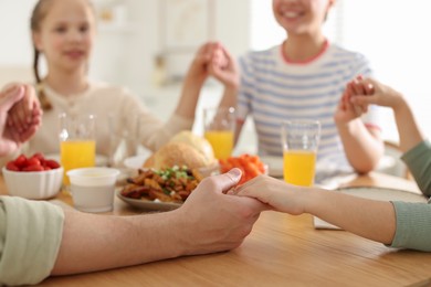 Photo of Family praying together before dinner at table indoors, closeup