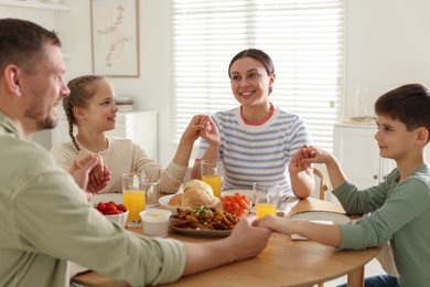 Photo of Family praying together before dinner at table indoors