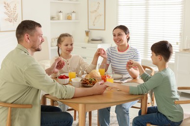 Photo of Family praying together before dinner at table indoors